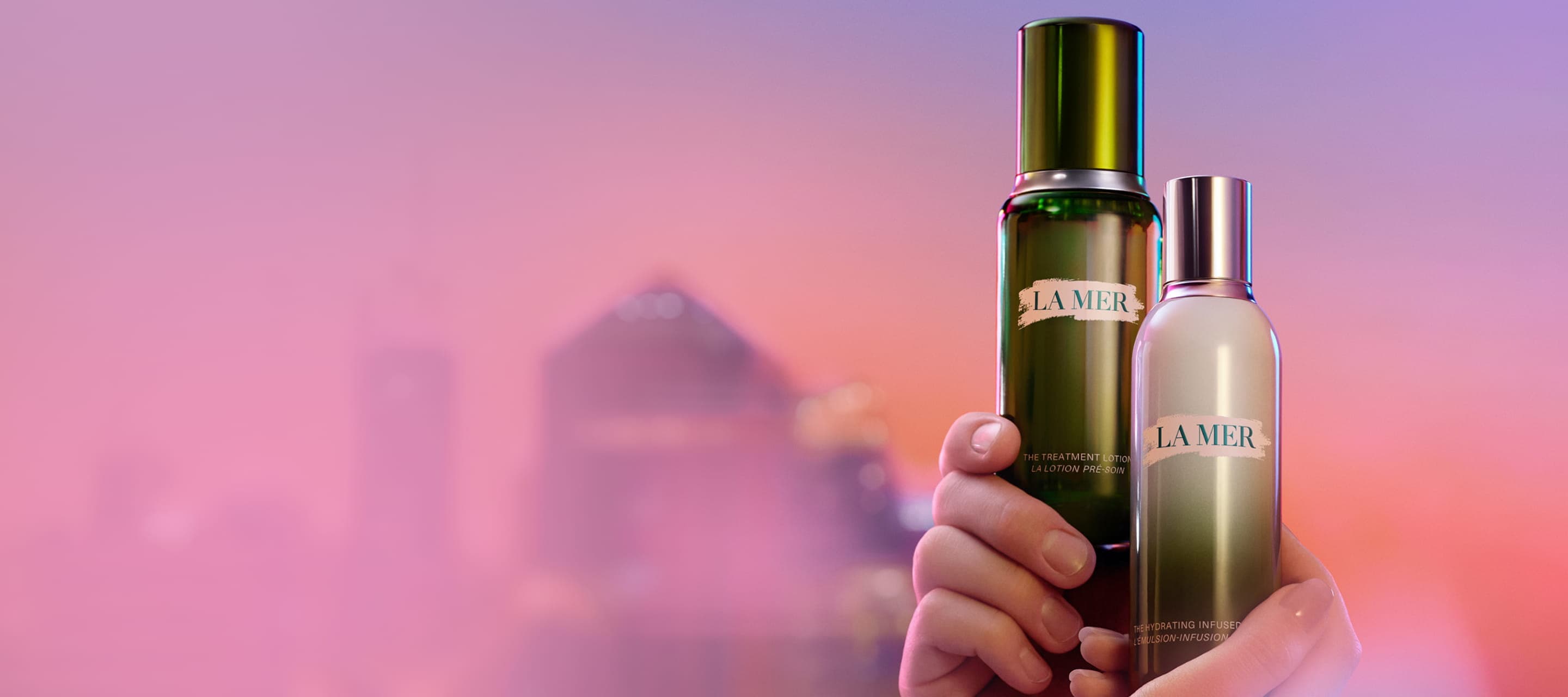 Selection of La Mer bestselling, held by hands, pink and purple backround