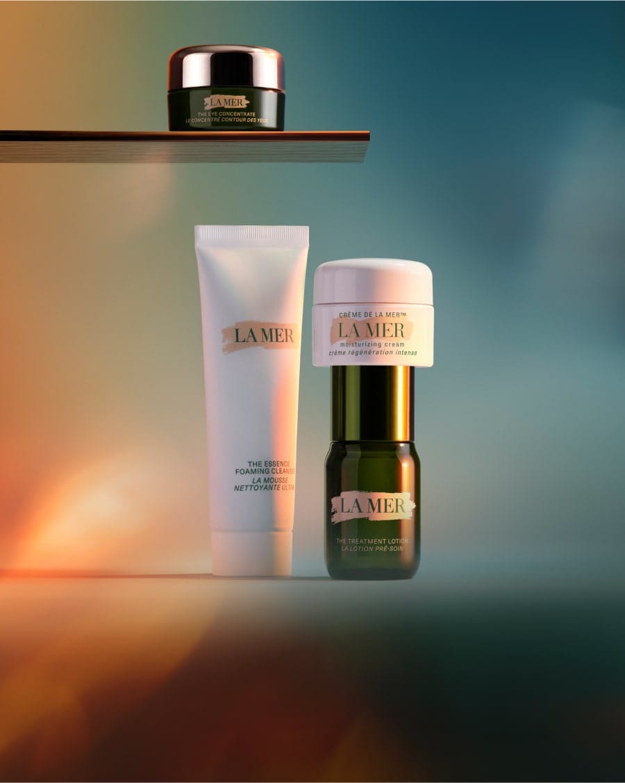 Selection of La Mer minis in a dynamic, twilight lit setting, with The Eye Concentrate mini on a glass shelf