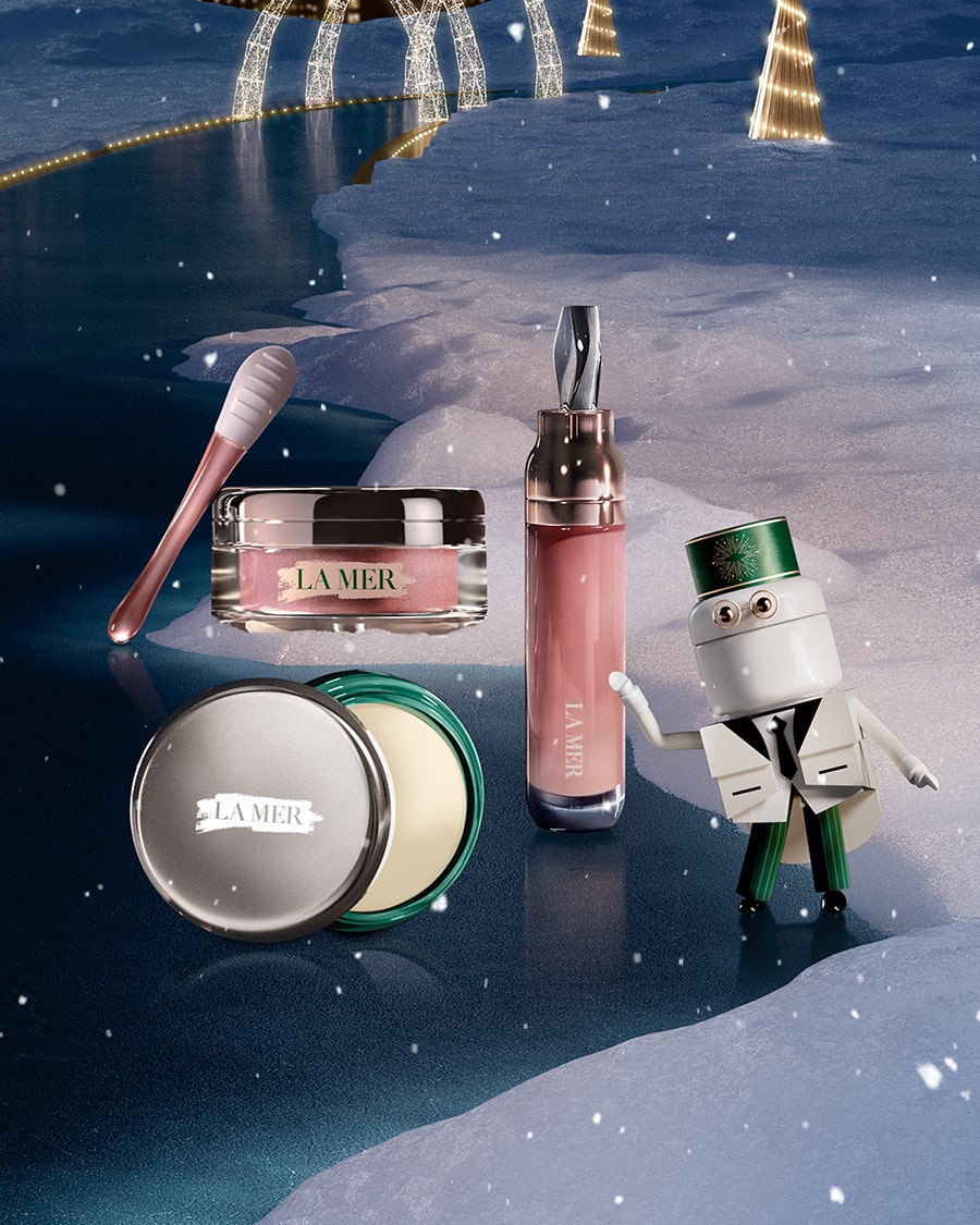 3 separate La Mer lip products nestled in snow, next to La Mer attendant caricature, with animated snow falling from the sky