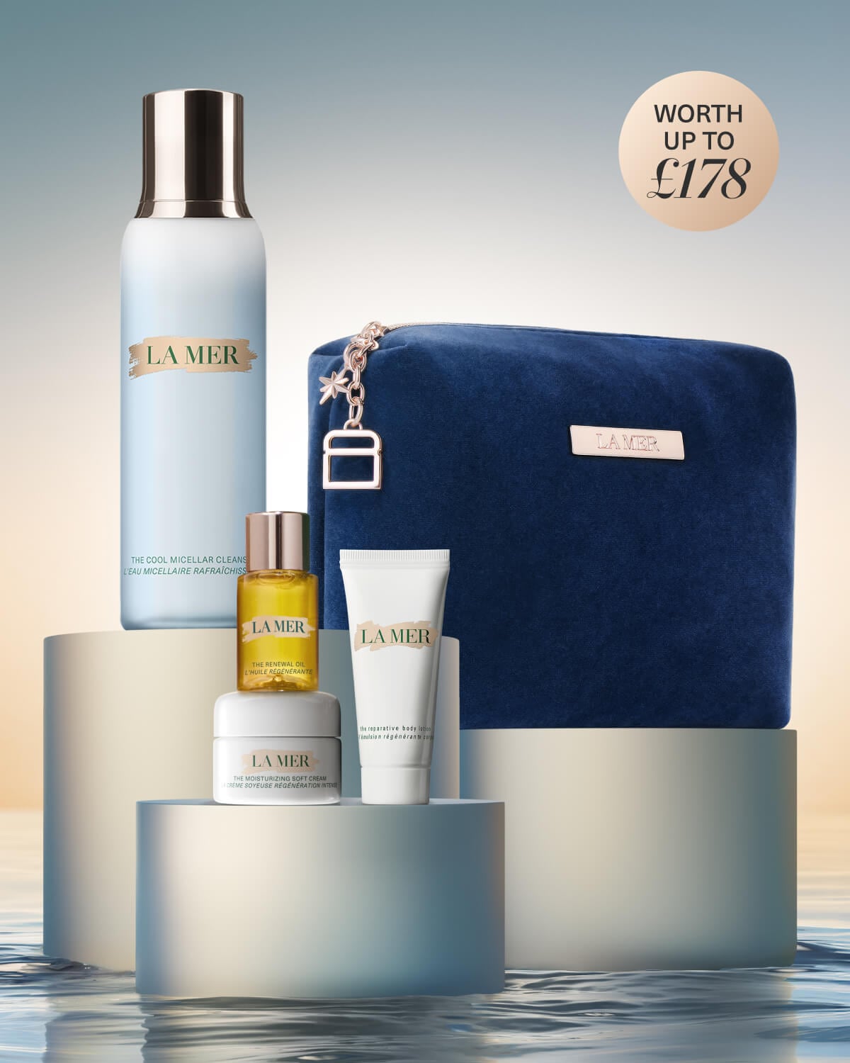 La Mer skincare gift set displayed on white blocks with a teal bag and products worth £242.