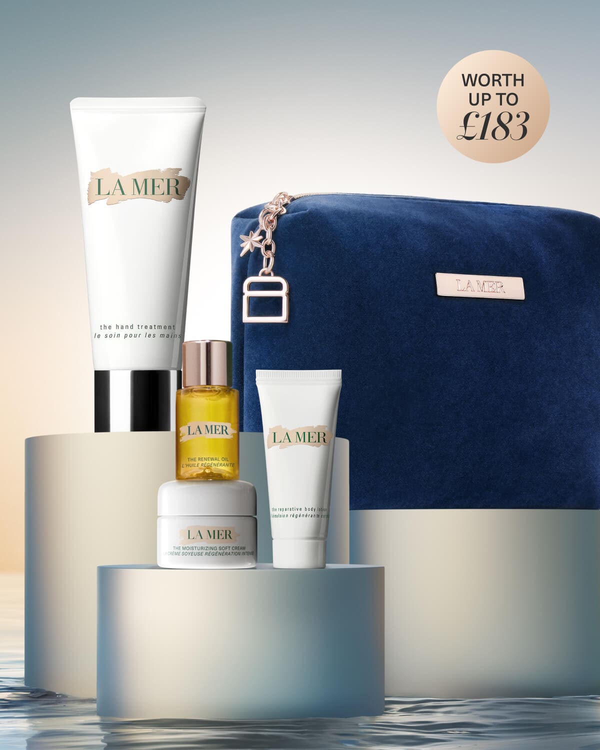 La Mer skincare gift set displayed on white blocks with a teal bag and products worth £185