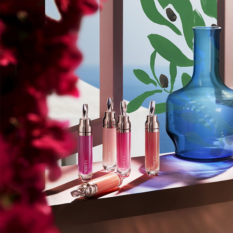 la mer lip products on shelf with a blue vase and red flowers